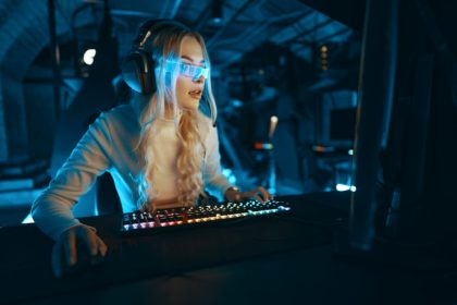 Blonde in cyberpunk glasses plays computer games, fascinated by technology and the virtual world.