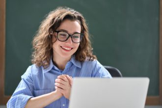 Happy young business woman feels excited about online result looking at laptop.